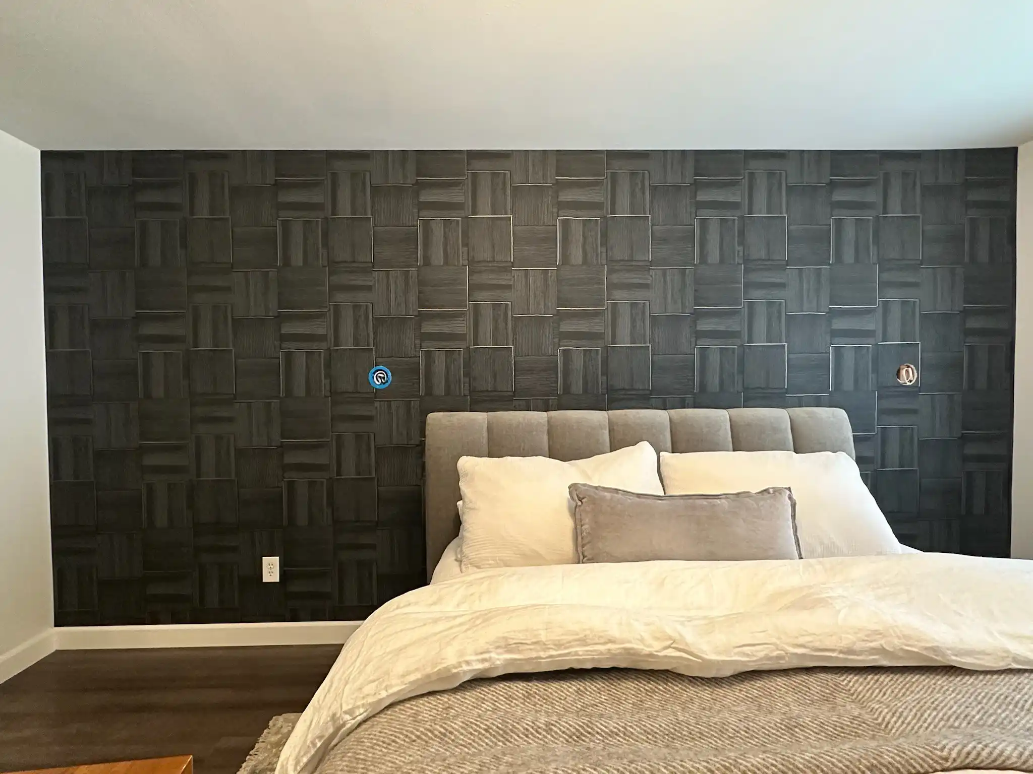 Charcoal geometric wallcovering behind a bedroom headboard